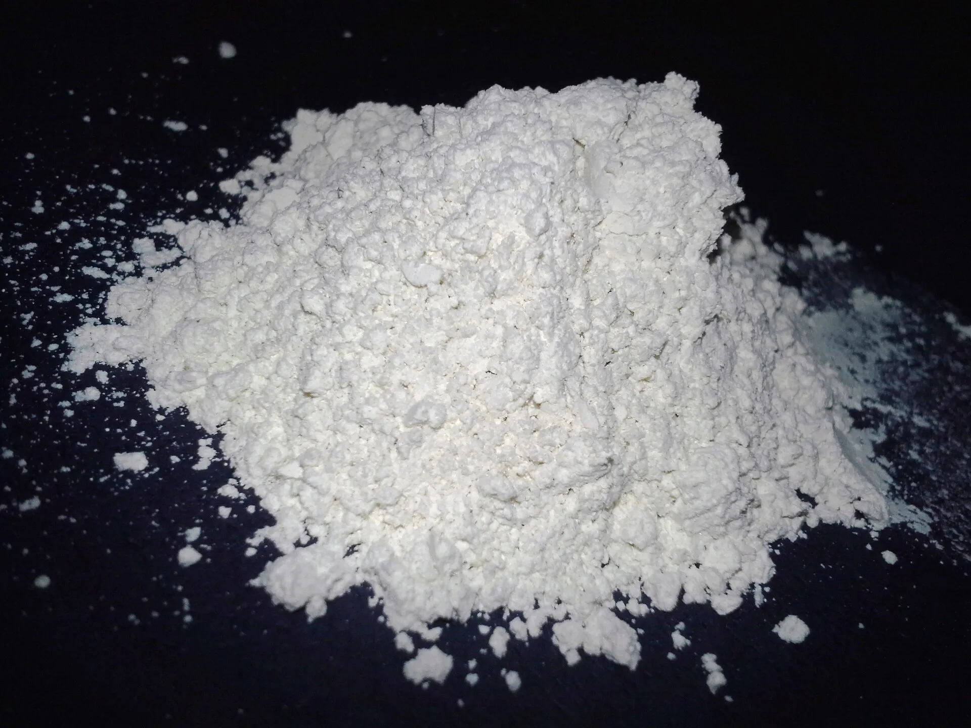 Petit tas de poudre blanche et fine de terre de diatomée sur fond noir